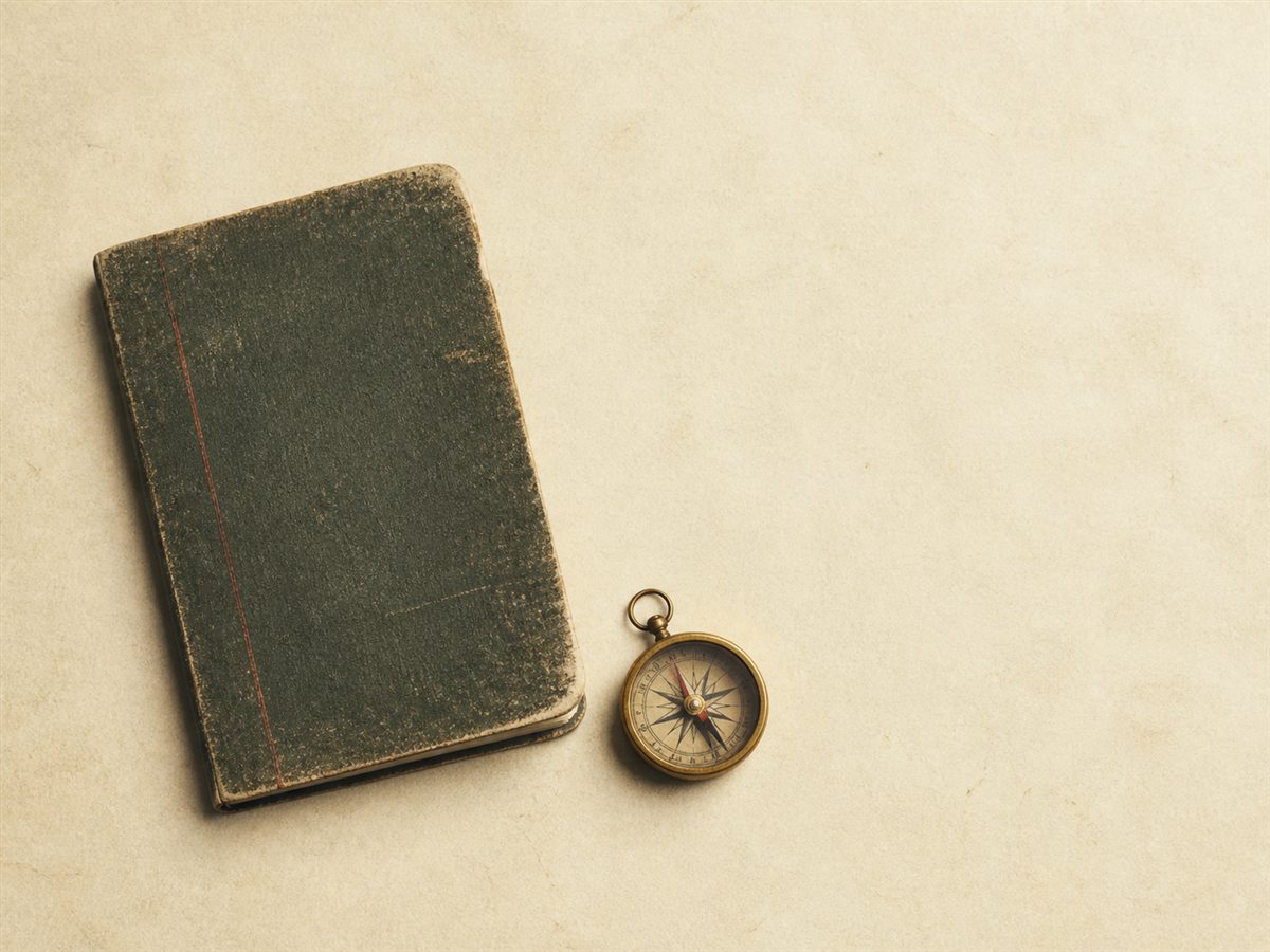 A worn field notebook beside a brass compass